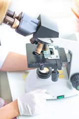 The lab technician looks into the microscope and records and analyzes the blood.