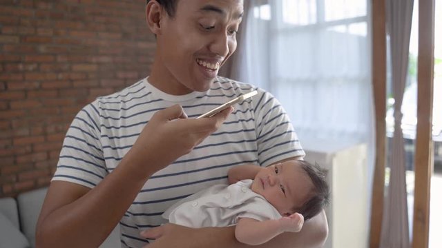 Young father with daughter taking photo using smartphone in the house