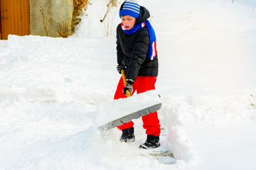 A young boy in the village cleans the snow and makes a walk.