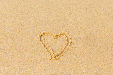 Valentine's day on a sunny beach. Heart drawn in the sand, concept of love. Relax on the sandy beach. Copy space.