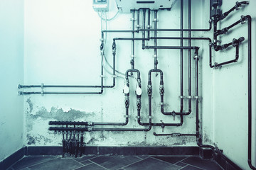 Old heat pipes room. Dramatic picture of a boiling room with damaged walls cause the mold