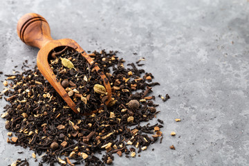 Dried black tea with cinnamon, ginger, pepper on a gray background