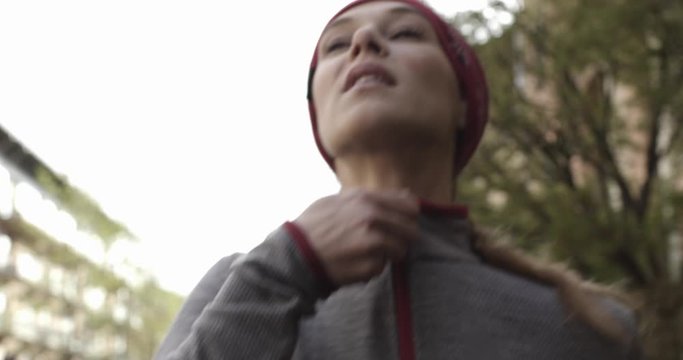 woman warming up for running training.woman running active along city street and park in cold season. Bad weather running athlete. Winter running in urban park.Back view.sporty woman run.