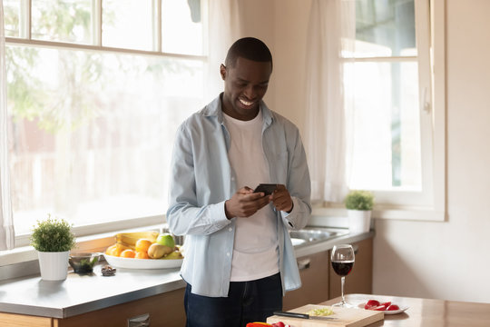 African American man use cellphone cooking in kitchen