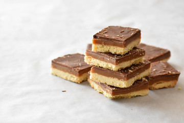 Millionaire's shortbread with chocolate and caramel on a parchment paper with copy space on the...
