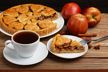 Homemade apple pie with cinnamon and cup of tea on wooden table. Shallow focus.