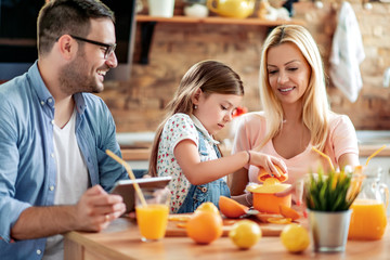 Cheerful young family drinking orange juice