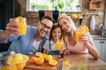 Cheerful young family drinking orange juice