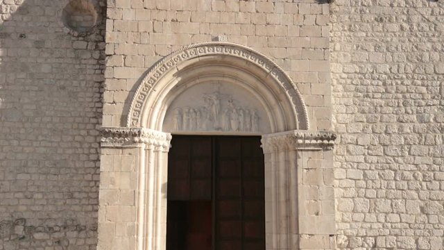 door of medieval church, tilt shot of door of cathedral in Venzone with crucifixion artwork (Italy)