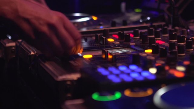Pan shot showing dj mixing music on sound console at nightclub