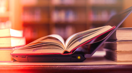 Stack of books with laptop on table in library.