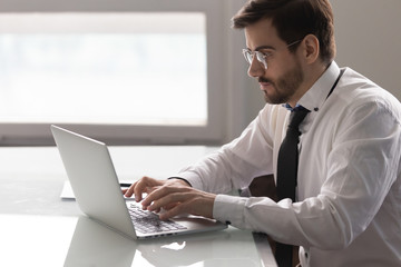 Concentrated male employee busy working at laptop