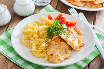 Chicken breast in batter with pasta on a white plate, selective focus