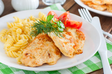 Chicken breast in batter with pasta on a white plate, selective focus
