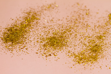 small gold sequins scattered on a pink background. background with beautiful shadow. poster. postcard view. space for your text. holiday. Christmas, women's day.