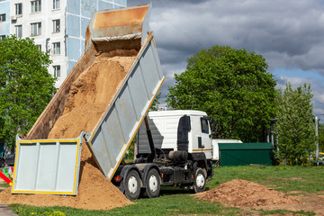 A truck pours sand onto a construction site.