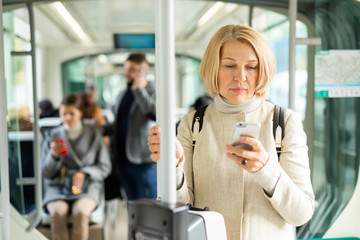 Fototapeta na wymiar Mature woman with phone in streetcar