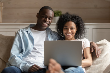 Happy african American couple relax on couch using laptop