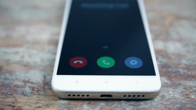Incoming call on white mobile phone on wooden surface