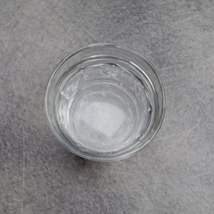 crystal clear glass of water on grey marble table background, top view