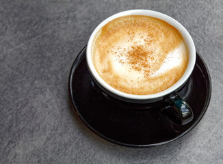 hot Italian cappuccino black cup on grey table background