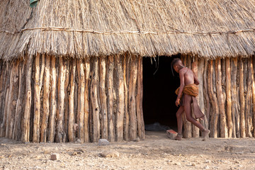A kid walks into a hut in a Himba tribal village in Namibia, Africa
