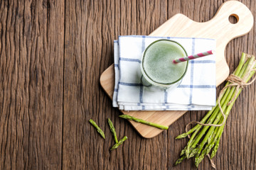 Fototapeta na wymiar Top view of healthy green smoothie asparagus on cutting board and wooden background. food and drink for health concept.