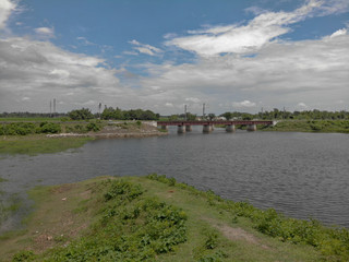 Fototapeta premium partially cloudy day , flowing river water with the rail bridge which adds to the beauty of the picture.
