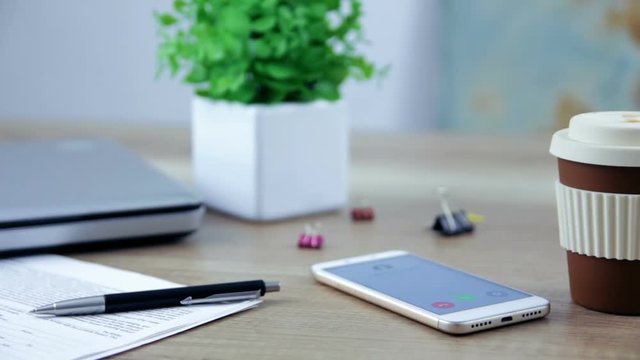 Smartphone with incoming  call on display that placed on table.