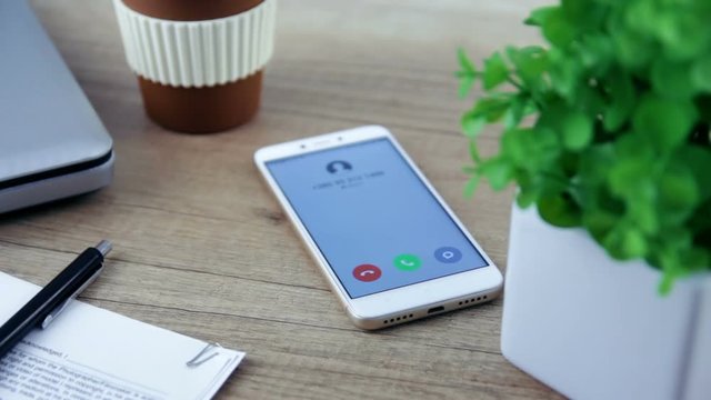Smartphone with incoming  call on display that placed on table.
