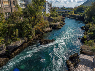River crossing the city of Mostar with the bridge in the background