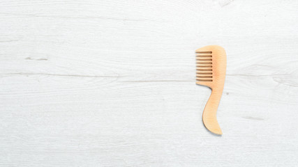 Wooden comb for hair on a white wooden background. Top view. Free space for your text.