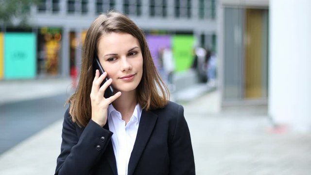Portrait of a young woman walking and talking on the phone