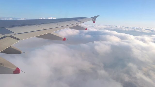 Airplane wing flying above the clouds  on the beautiful sky.Window view on travel trip. 4K, UHD video