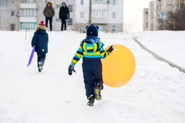 A little boy rides downhill on a sled in winter. Christmas holidays child outdoor activities