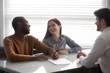 Excited multiethnic couple closing deal with banker specialist in office