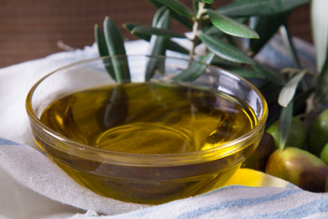 glass vessel with extra virgin olive oil and olives with branch