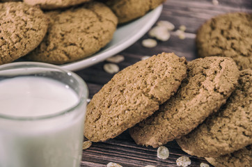 oatmeal cookies and a glass of milk on a wooden background.