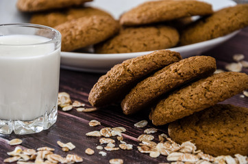 oatmeal cookies and a glass of milk on a wooden background.