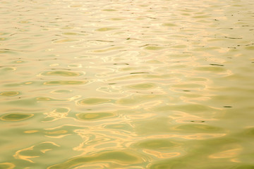 Abstract photo of surface water of sea or ocean at sunset time with golden light tone.