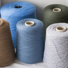 Dark Multi-colored bobbins of wool yarn for hand and machine knitting