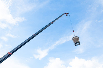 Obraz premium Cement or concrete bucket hanging on wire at construction site with blue sky background