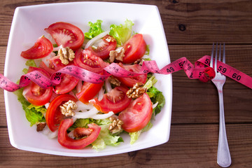 lettuce and tomato salad with tape measure, healthy diet concept