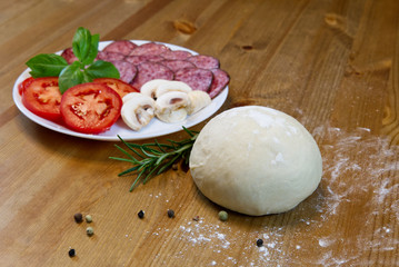ingredients for cooking italian pepperoni pizza at home. dough, mozarella, salami, tomato, basil, olive oil, rosemary, pepper, garlic