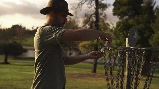 Man resting and stretching on frisbee golf goal