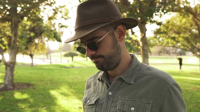 Man wearing hat and sunglasses talking to camera holding frisbee