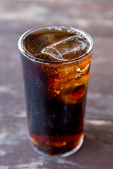 Pop or cola water in glass on the wooden table.