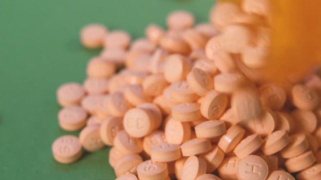 pills in orange  bottle.  pills are falling out from the bottle on the table. pills on a green background. Pills. Medicine and healthy. Close up of macro