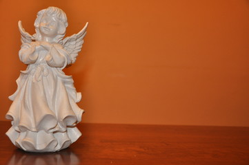 Angel white statue isolated on orange surface