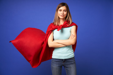 Woman in red superhero cloak standing on empty blue background